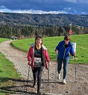 Zwei Wanderer auf einem Schotterweg auf einer Alm