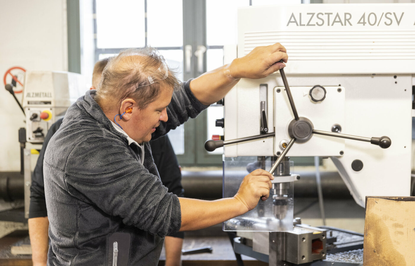 Ein Mann bedient eine Bohrmaschine in einer Werkstatt
