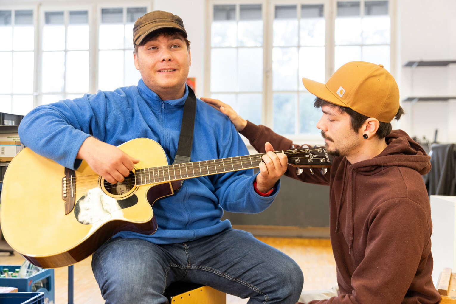 Gitarre spielen Ein Mann spielt Gitarre, ein anderer hört zu.